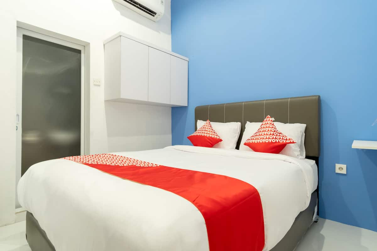 A neatly made bed with a white and red bedspread, two pillows with red and white patterns, and a grey headboard.