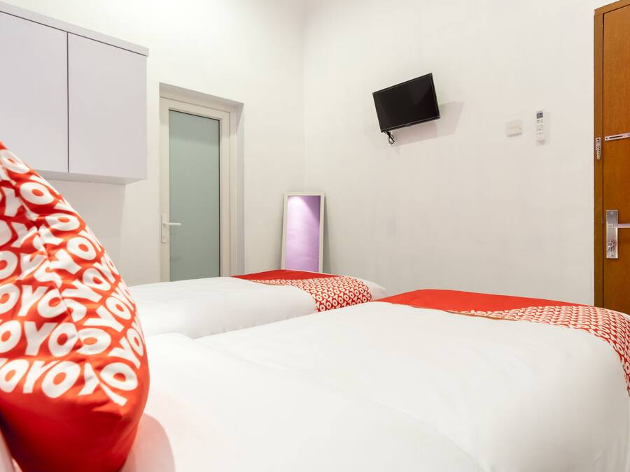 A hotel room with two beds, a TV mounted on the wall, and a wooden door.
