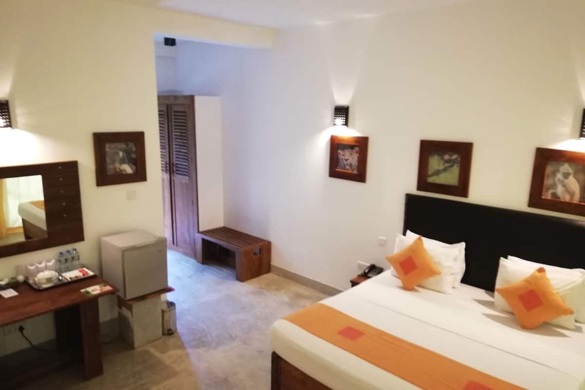 A hotel room with a bed, bedside table, desk, and wardrobe.