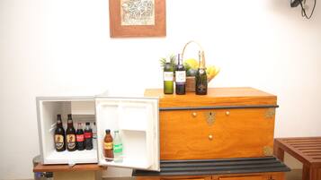 Un refrigerador con bebidas y un cofre de madera con botellas encima.