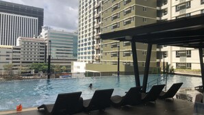 A swimming pool with lounge chairs and a covered area, surrounded by high-rise buildings. - I.T PARK CEBU TWIN BED DELUXE FREE FAST WIFI & POOL (Cebu City)