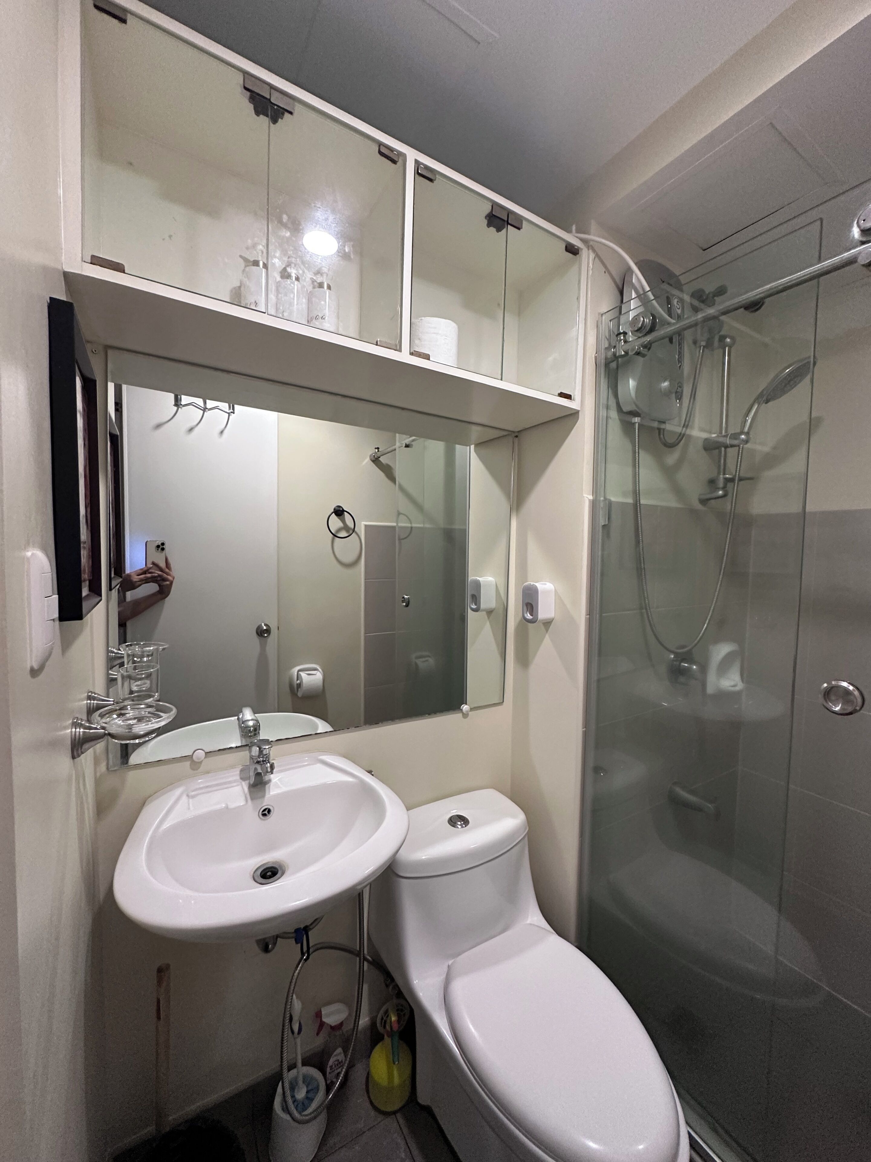 A bathroom with a glass-enclosed shower, a white sink, and a toilet.