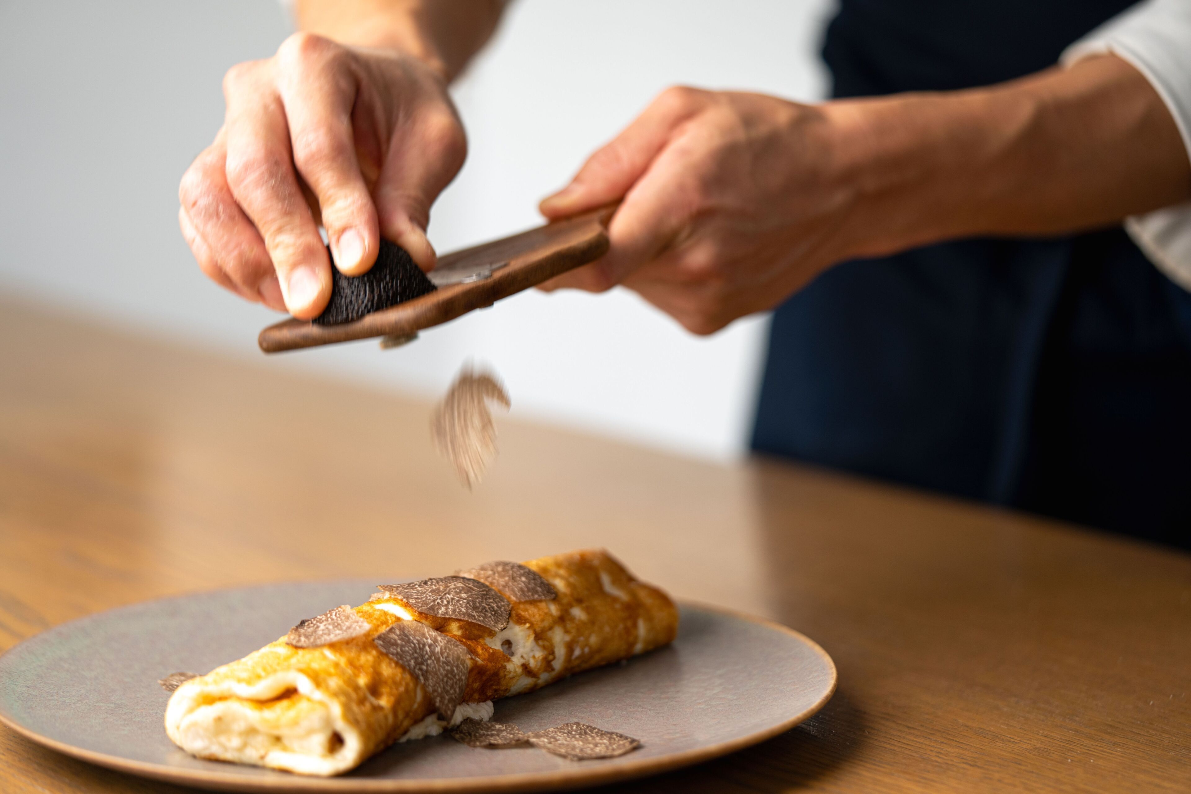 A person cutting a rolled omelette on a plate.