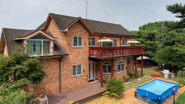 A two-story brick house with a balcony, a covered patio, and a swimming pool. - The Hue Largo Bundang (Yongin)