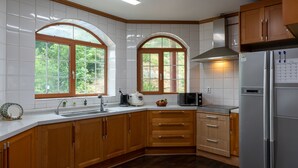 A kitchen with wooden cabinets, a stainless steel refrigerator, and a window with a view of greenery. - The Hue Largo Bundang (Yongin)