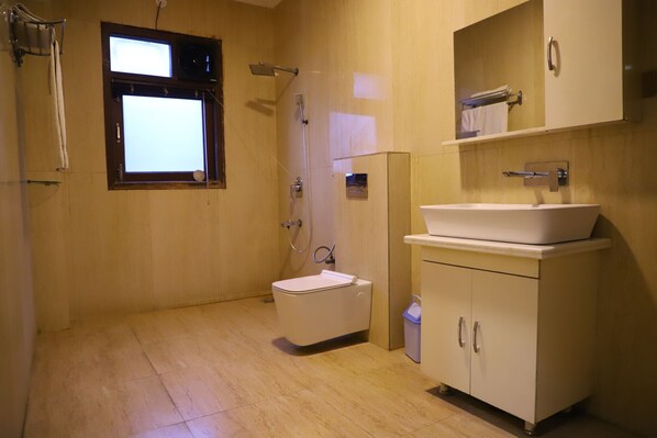 A bathroom with a toilet, a sink, and a shower. - Kumar Residency (Noida)