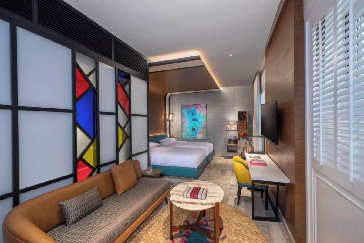 A hotel room with a bed, sofa, TV, and a small table.