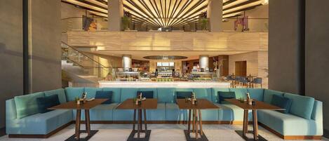 A modern lobby with a central seating area, a staircase, and a reception desk.