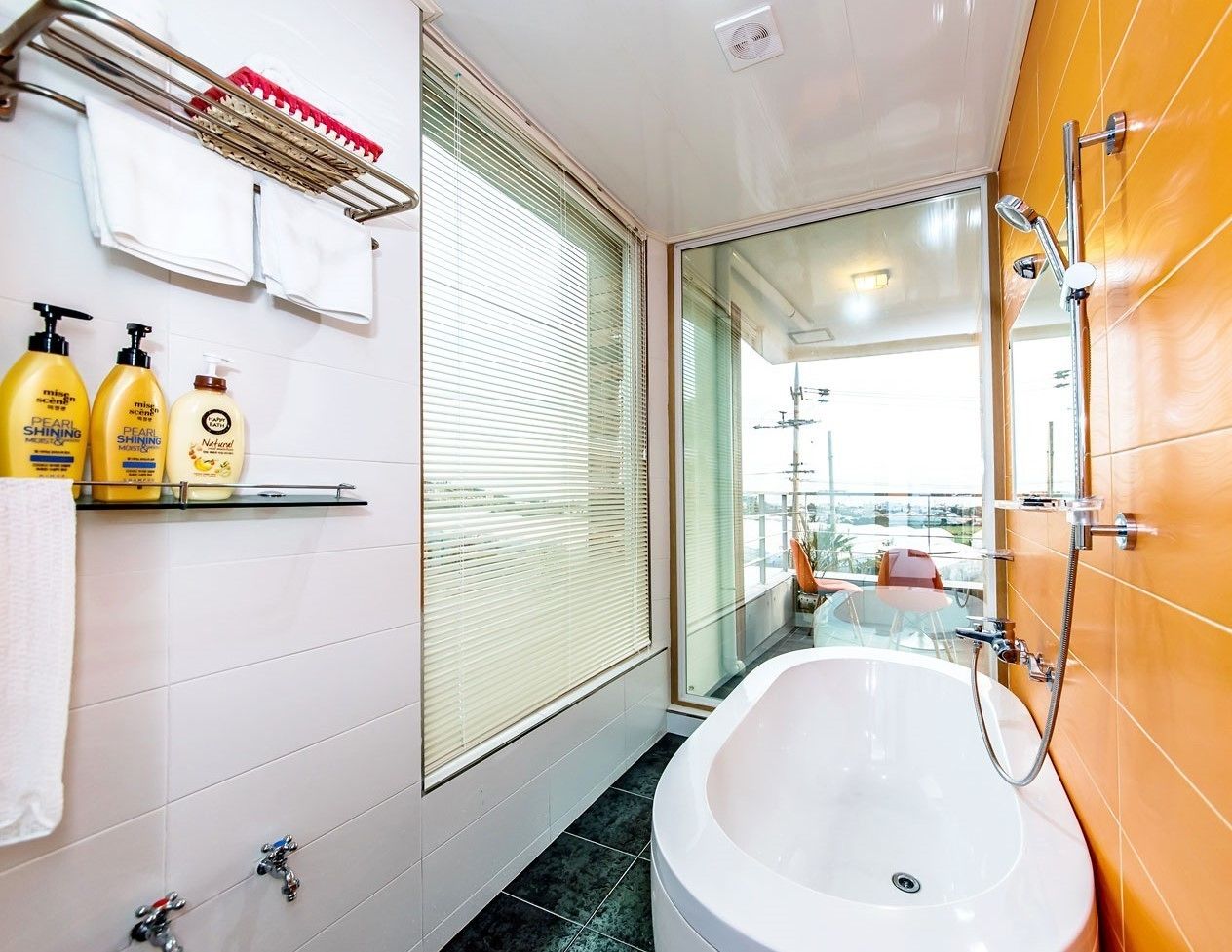 A modern bathroom with a bathtub, a glass shower enclosure, and a window with blinds.