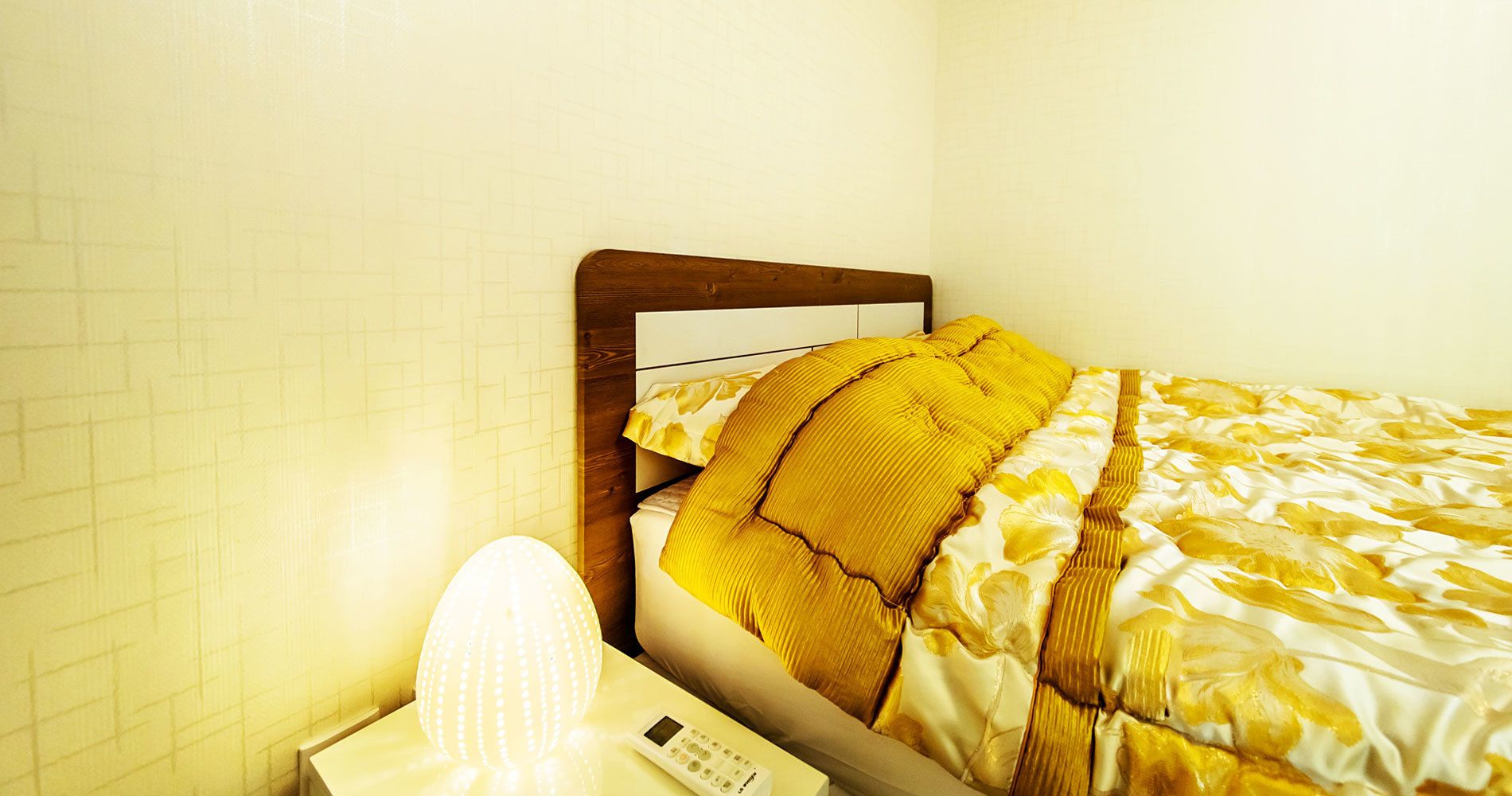 A hotel room with a bed, a nightstand, and a lamp.
