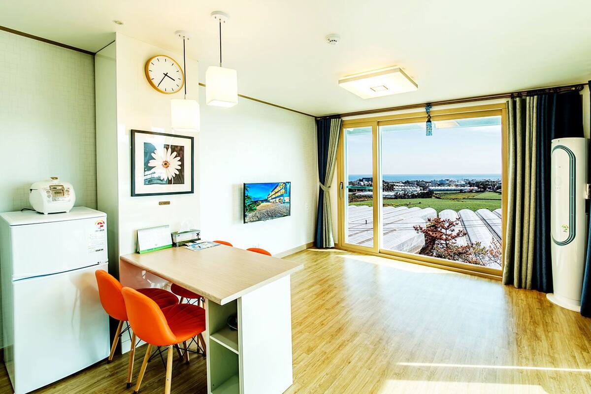 Una cocina moderna con comedor, un reloj y un amplio ventanal con vistas al campo.