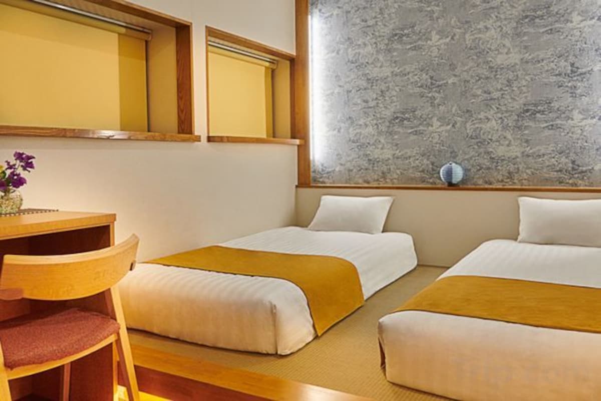 Une chambre d’hôtel avec deux lits, un bureau en bois et une fenêtre donnant sur un paysage agréable.