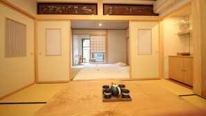 A traditional Japanese room with tatami flooring, a futon bed, sliding doors, and a wooden table with a tray of tea cups. - Ichinomatsu Japanese Modern Hotel (Takayama)