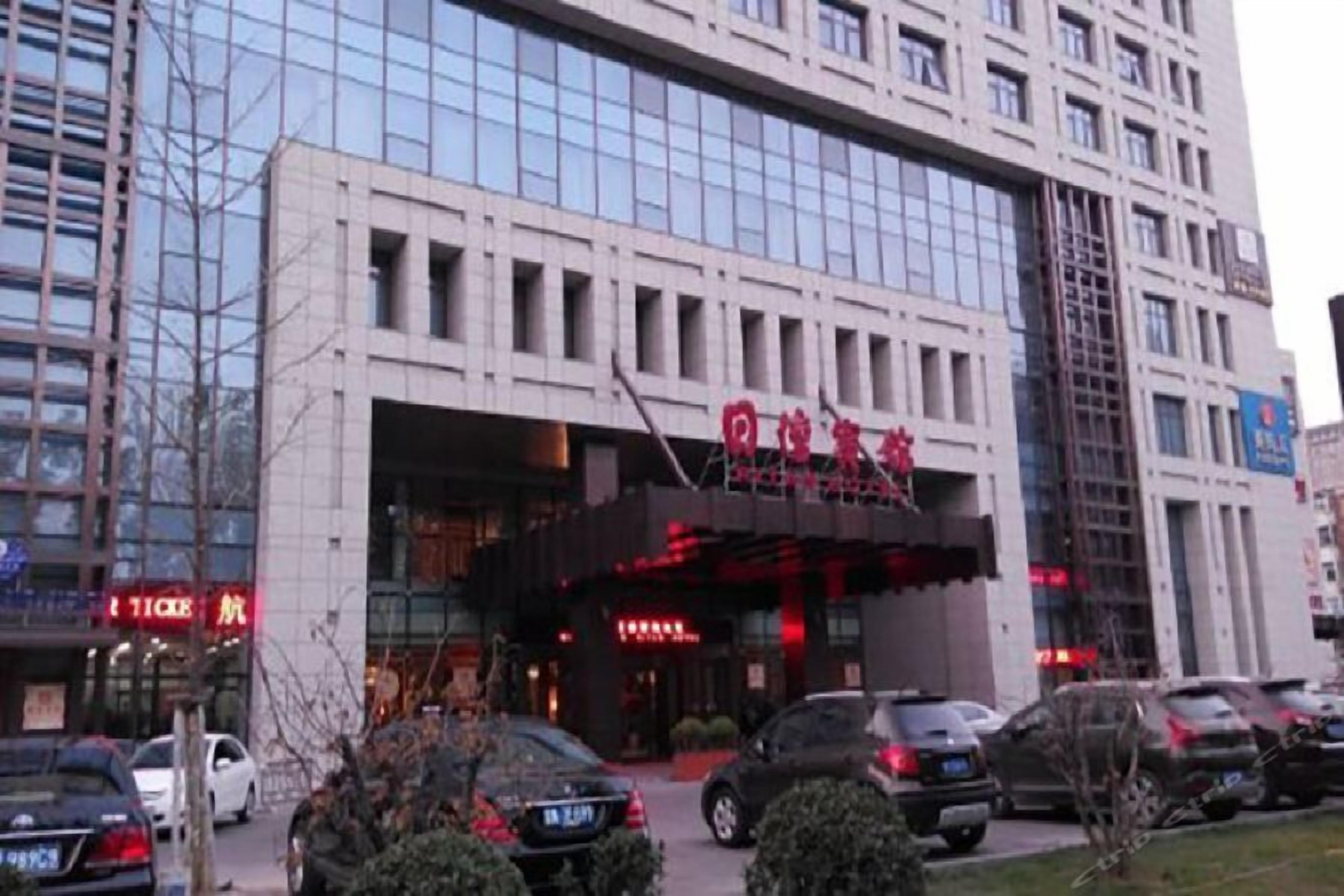 Un edificio de varios pisos con una entrada amplia y un toldo rojo.