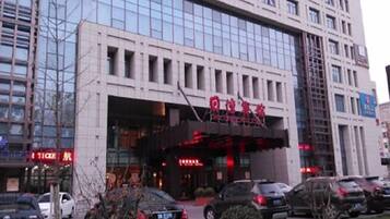 Un edificio de varios pisos con una entrada amplia y un toldo rojo.