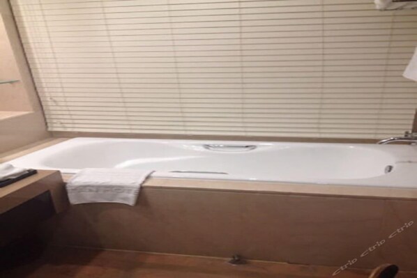 A bathroom with a bathtub, a towel, and a wooden counter. - Ritan Hotel (Beijing)