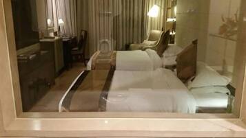 Una habitación de hotel con una cama, un escritorio, una silla, un espejo y una ventana con cortinas.
