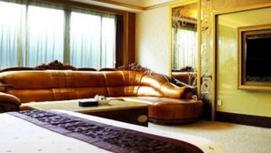 Ein geräumiges Hotelzimmer mit einem großen Bett, einer Ledersofa, einem Fernseher und einem großen Spiegel.