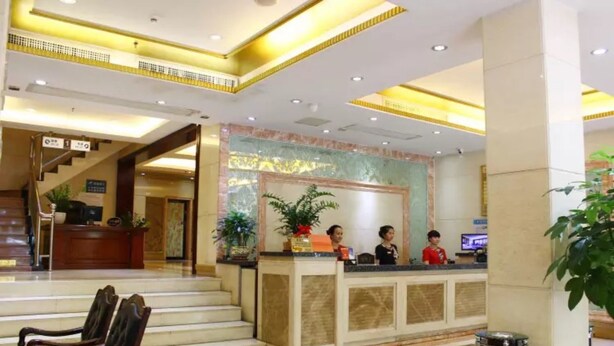 Ein Hotel-Empfangsbereich mit Marmorboden, einer Rezeption, einer Treppe und einem Warnhinweis auf dem Boden.