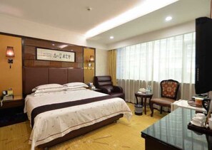 A hotel room with a large bed, a desk, a chair, and a television. - Zhuhai Xinhualian Business Hotel (Zhuhai)