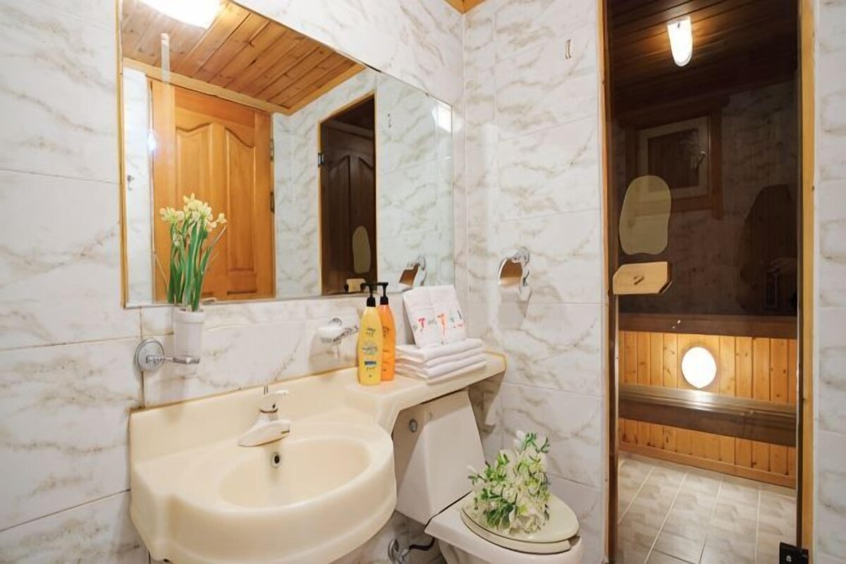A bathroom with a marble sink, mirror, wooden vanity, and a shower area.