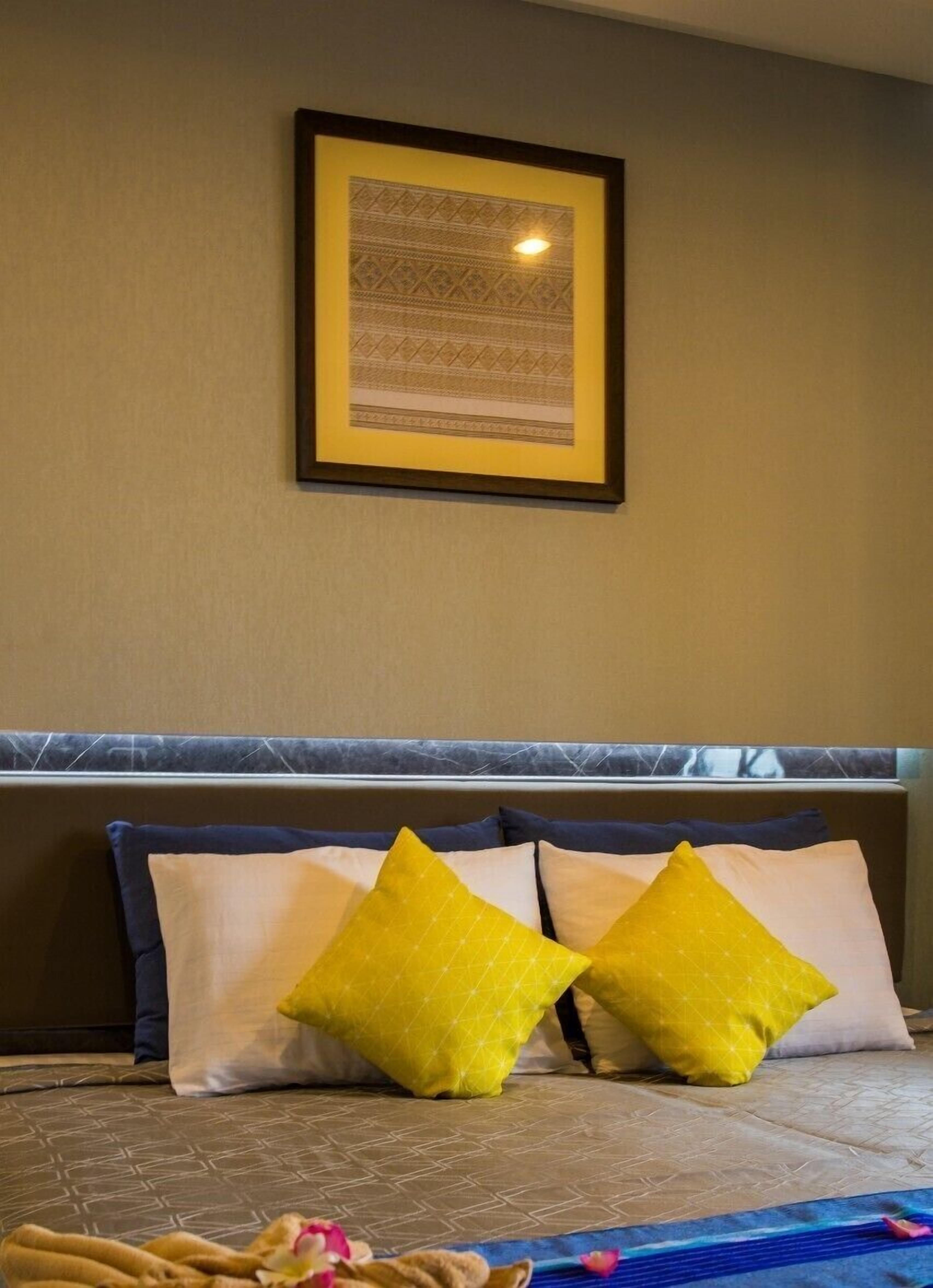A hotel room with a bed, a headboard, and a framed picture on the wall.