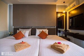 A hotel room with two beds, a flat-screen TV, and a large mirror.