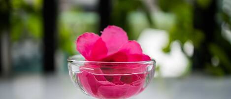 Un saladier en verre transparent contenant des pétales de rose roses.