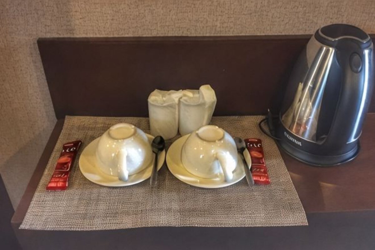 Una mesa con un hervidor, dos teteras y dos tazas de té sobre un mantel individual.