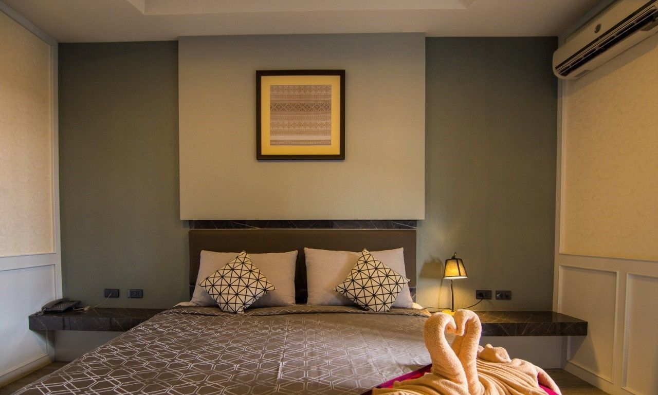 A neatly arranged hotel room with a bed, a bedside table, a lamp, and a framed picture on the wall.