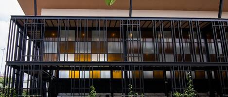 A modern building with a balcony and a pool in front.