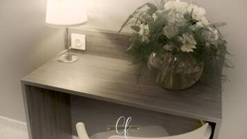 Un baño con tocador de madera, una silla blanca y una planta en maceta con flores blancas.