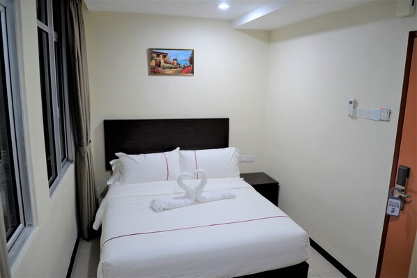 A hotel room with a neatly made bed, a painting on the wall, and a door with a lock. - DCozy Hotel (Perai)
