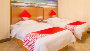 Una habitación de hotel con dos camas, un cuadro de una playa en la pared y una lámpara en el techo.