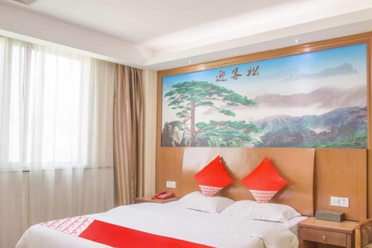 A hotel room with a large bed, a nightstand, a telephone, and a painting on the wall.