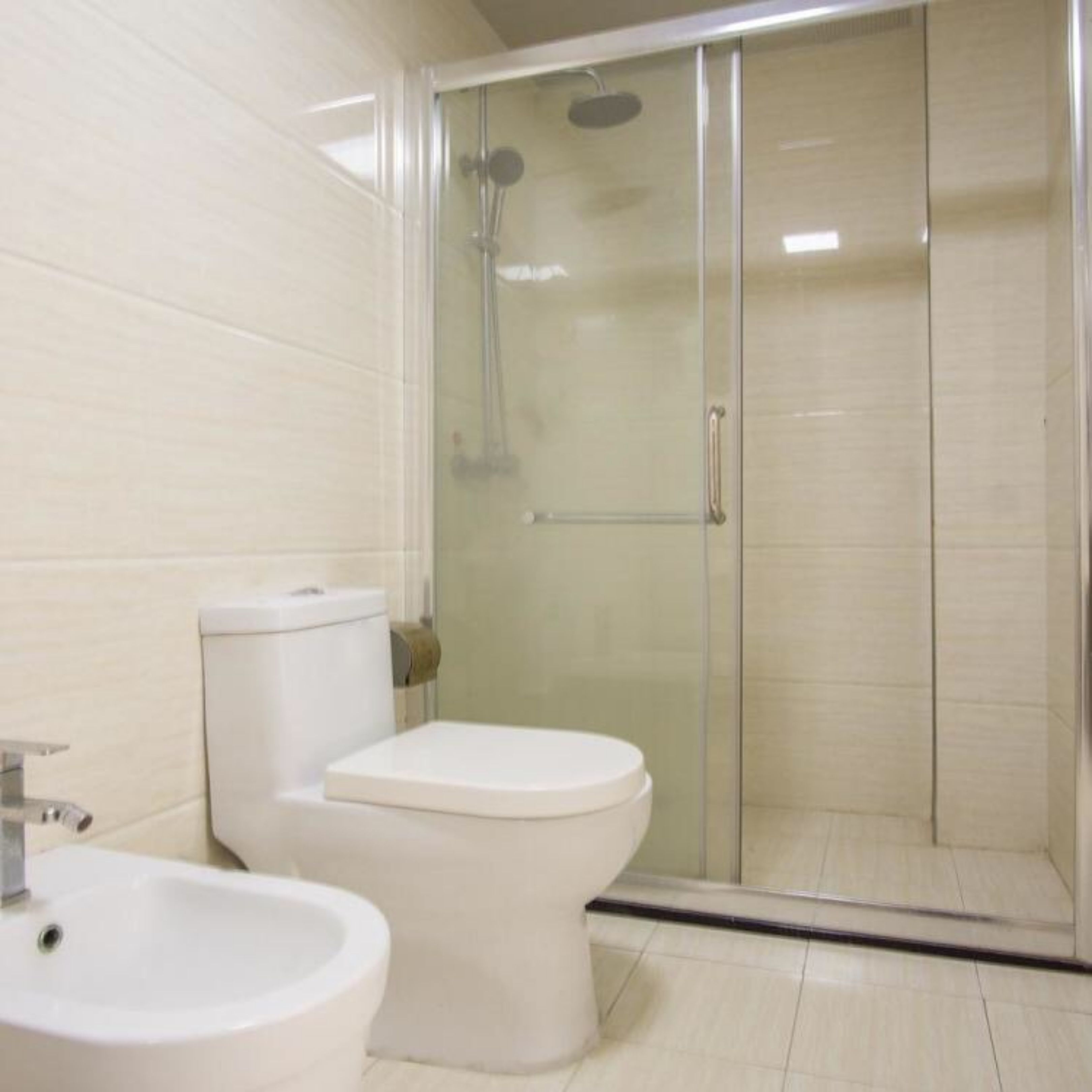 A bathroom with a toilet, sink, and glass-enclosed shower stall.