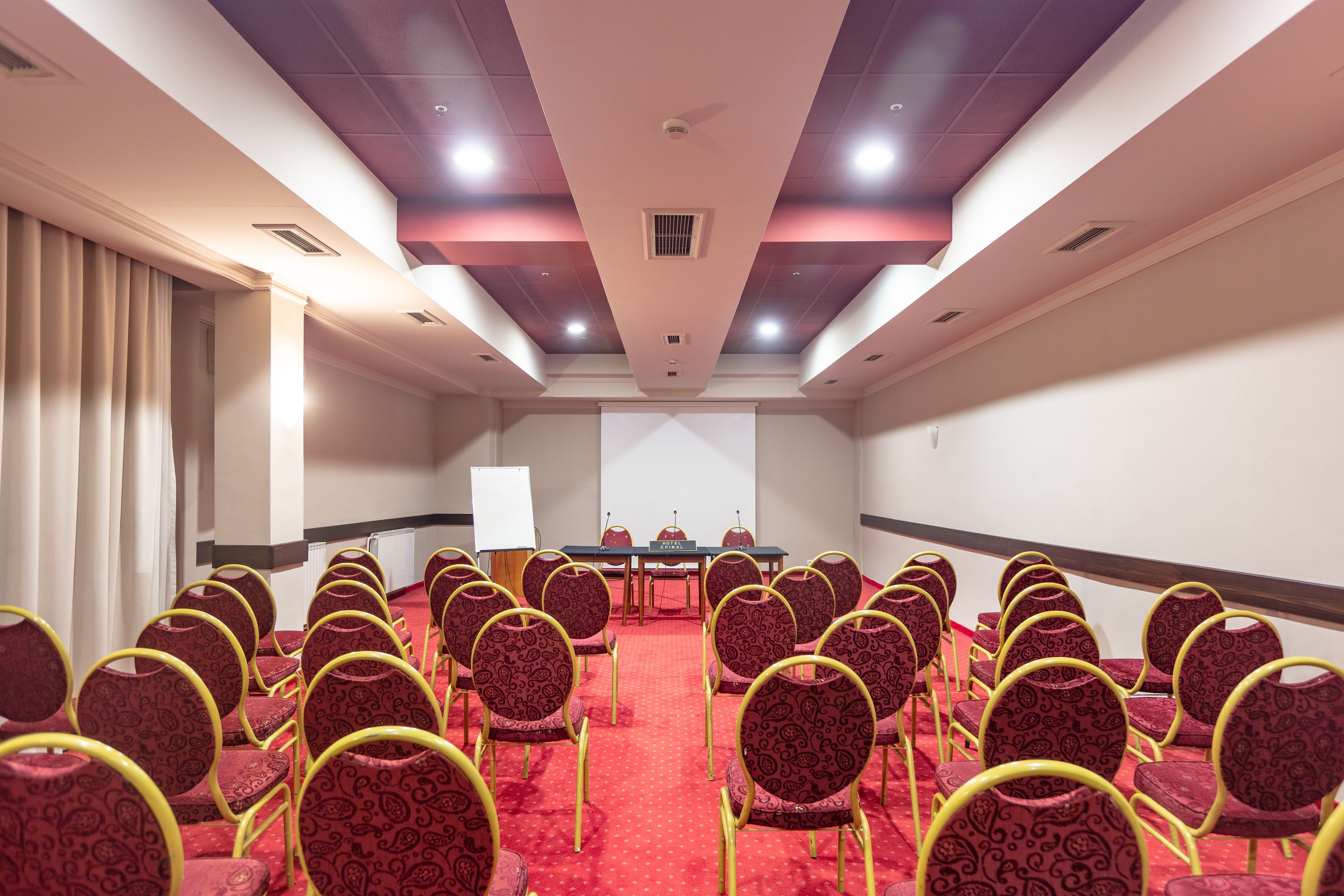 A conference room with rows of chairs, a table, and a projector screen.