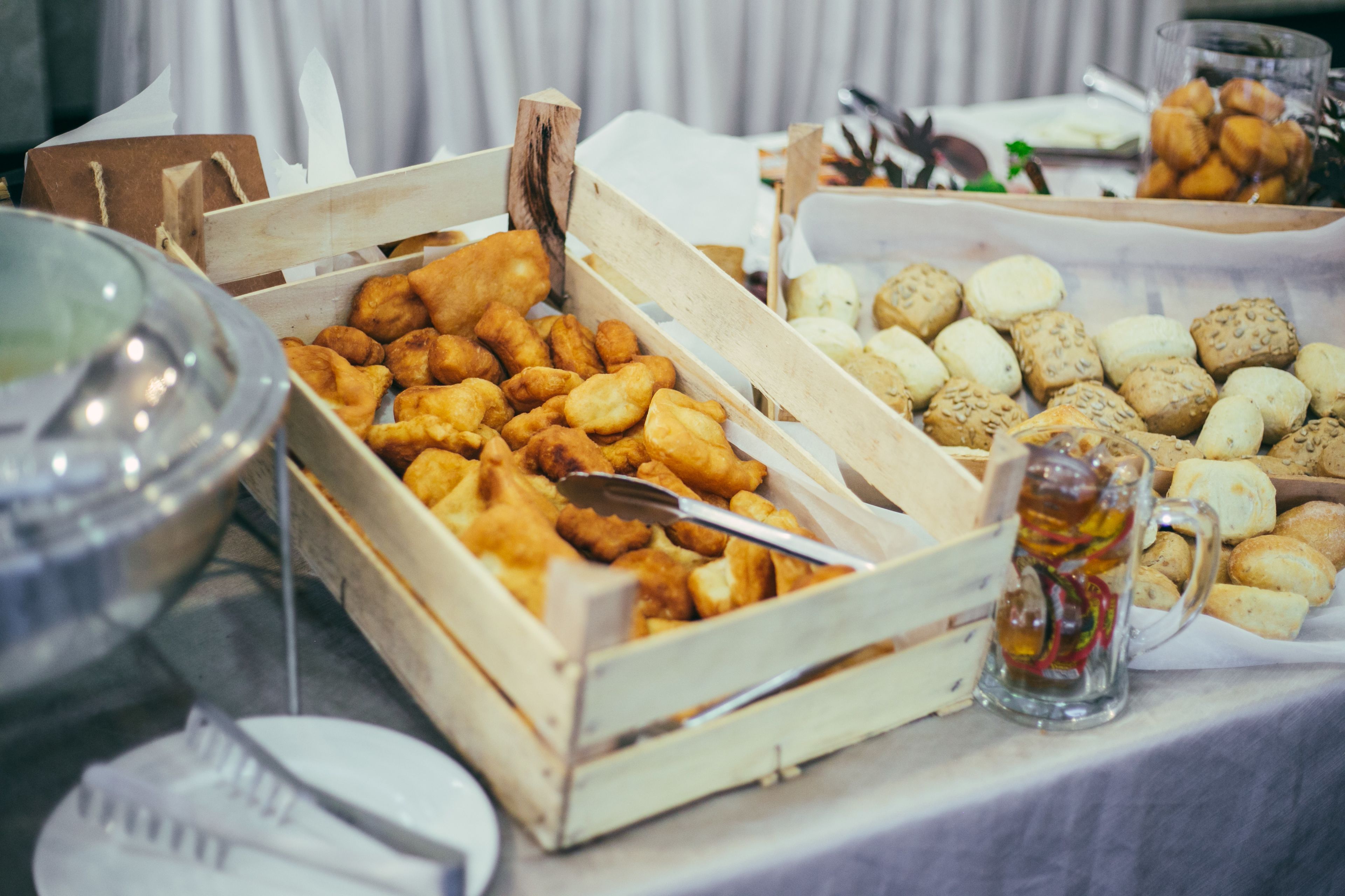 Une table de buffet proposant divers plats, notamment des aliments frits, du pain et une carafe de bière.