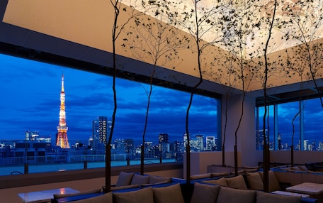A modern hotel room with a large window offering a view of the Eiffel Tower at night.