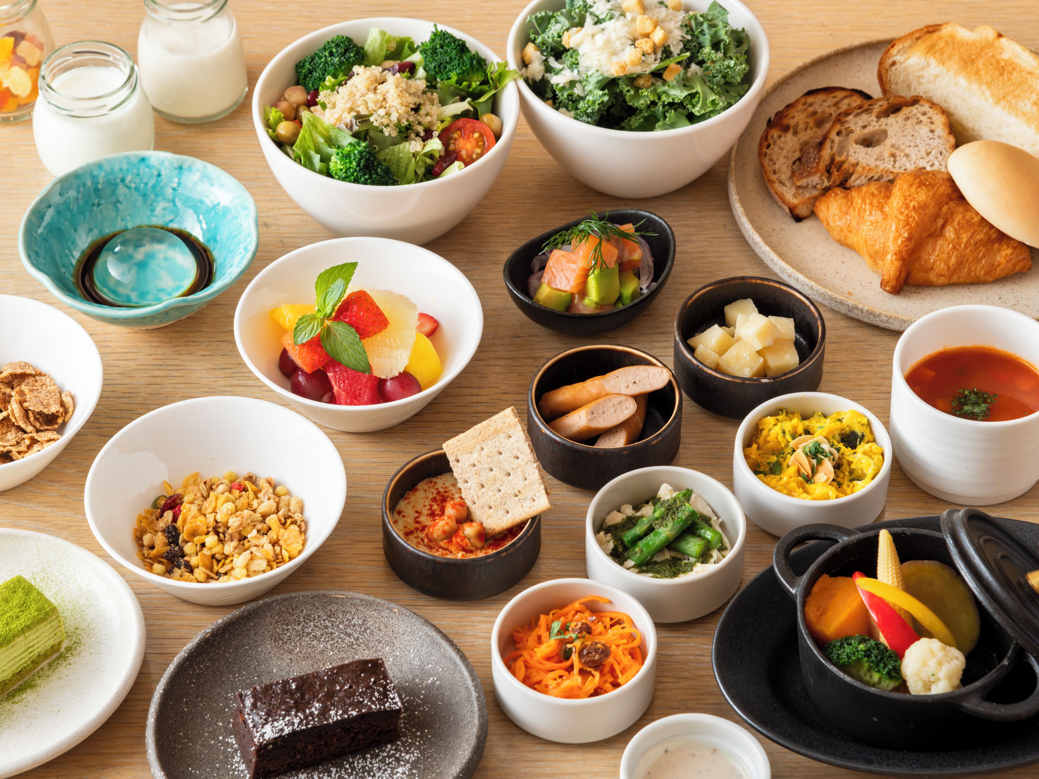 A variety of dishes including salads, bread, and desserts on a wooden table.