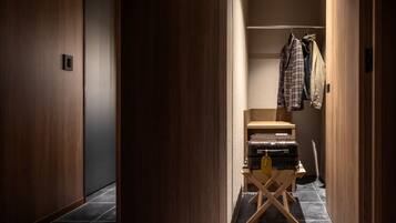 Un couloir aux murs en bois, avec un sol carrelé, un porte-manteau sur lequel sont accrochés des vêtements et une valise posée sur un présentoir en bois.