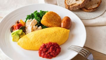 Un piatto con un'omelette, verdure e salsa rossa a parte.