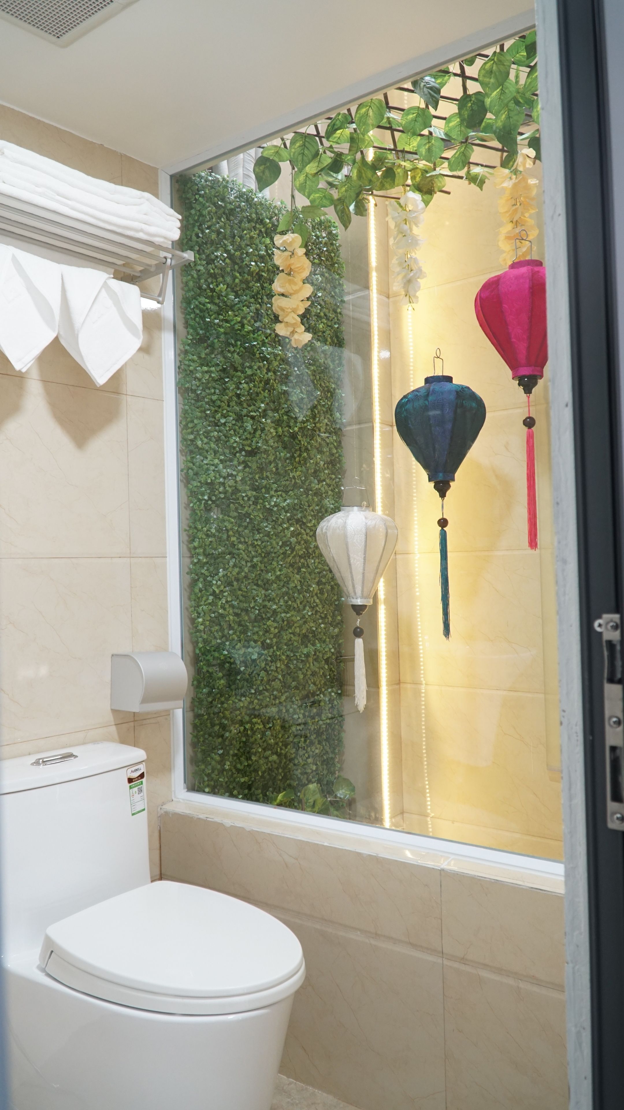 A bathroom with a toilet, a glass shower enclosure, and decorative hanging lanterns.
