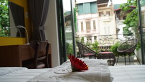 A hotel room with a bed, a desk, and a view of the outside balcony. - Hanoi La Cascada House & Travel (Hanoi)
