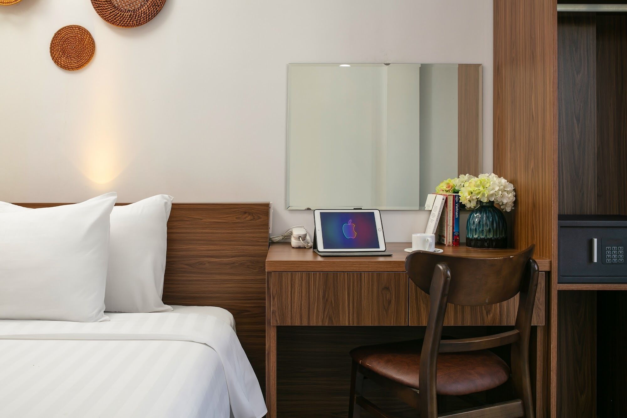 Une chambre d’hôtel équipée d’un lit, d’un bureau avec un ordinateur portable, d’une chaise, d’un miroir et d’un coffre-fort.
