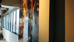 A corridor with large windows, a wall-mounted artwork, and a wooden floor. - Hanoi La Cascada House & Travel (Hanoi)