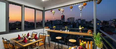 Un espace repas avec vue sur la ville, de grandes fenêtres et un ventilateur de plafond.