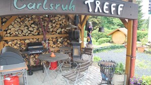 A covered outdoor area with a grill, seating, and a sign that reads "Carlsruh TREEF". - Hotel Carlsruh (Braunlage)