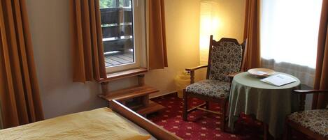 Una habitación de hotel con cama, una silla, una mesita y una ventana con cortinas.