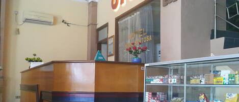 A hotel reception area with a wooden desk, a glass display case with various products, and a sign that reads "OYO HOTEL MEXICO SANTA ROSA 2019".